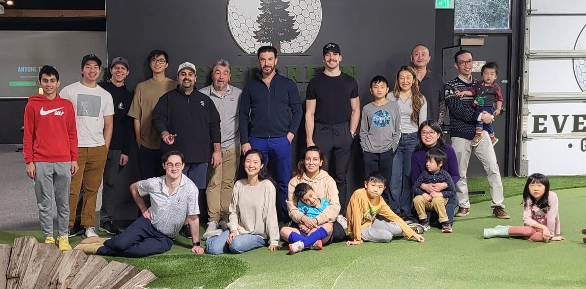 Eventcore team at an event, group of people standing together on a green grass and black backdrop, smiling